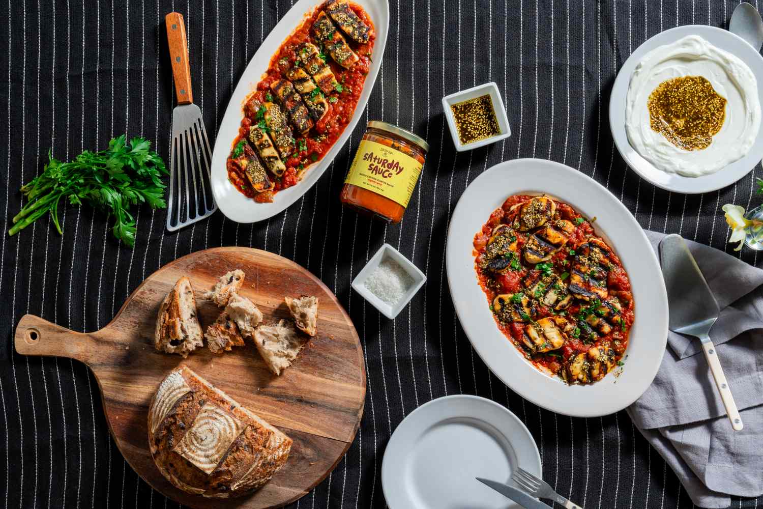 sababa saturday sauce with grilled eggplant and bread on black striped cloth