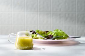 A jar of vinaigrette near a plate of salad