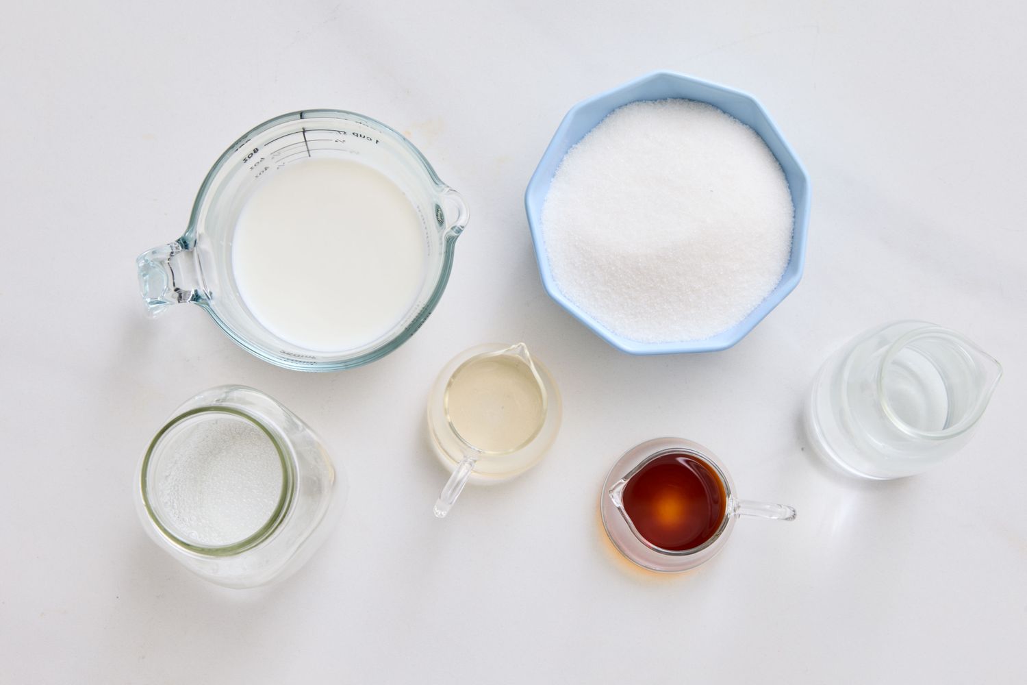 Ingredients measured in separate containers on a countertop including milk sugar and additional elements for a recipe