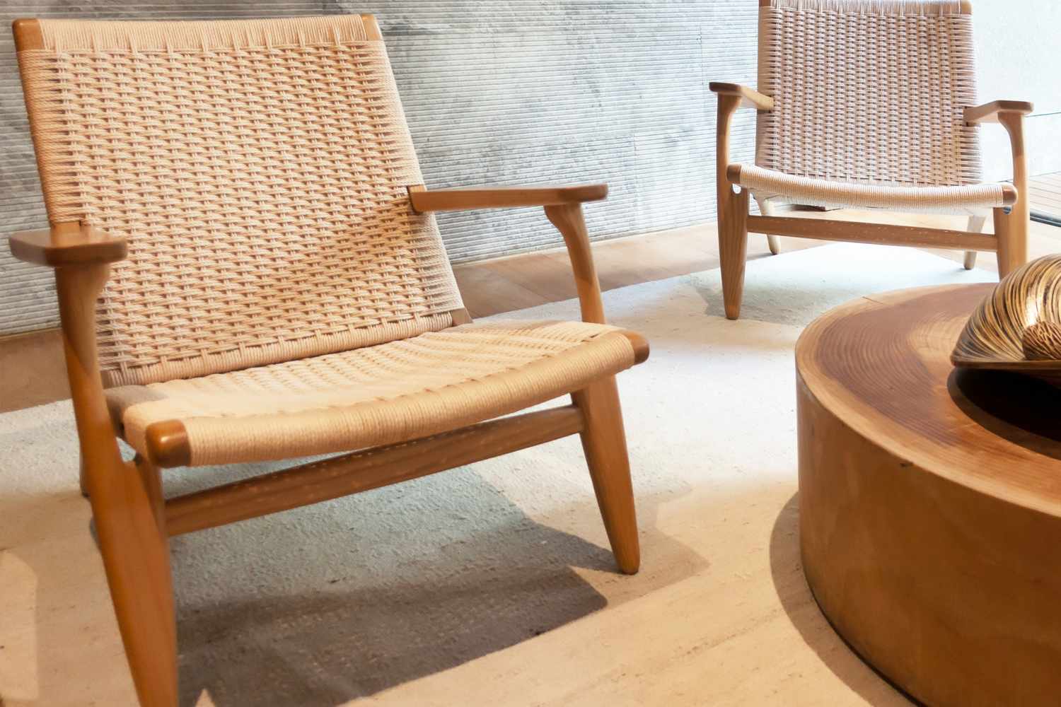Two wooden chairs with woven seats and backs positioned near a circular wooden table