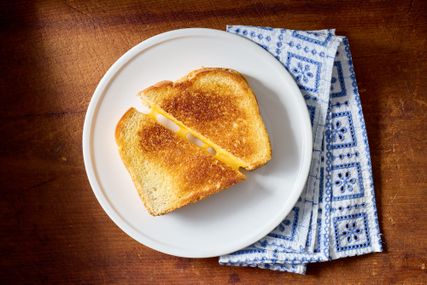 Grilled cheese sandwich cut in half on a white plate placed on a patterned blue napkin