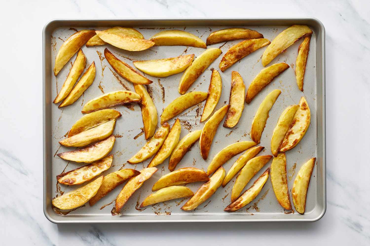 Baked roasted potato wedges on baking sheet