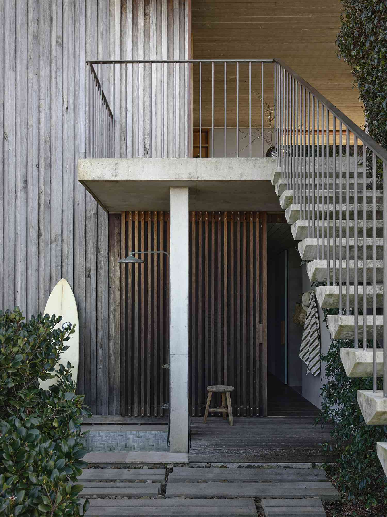 Coastal outdoor shower with wood slats and surfboard