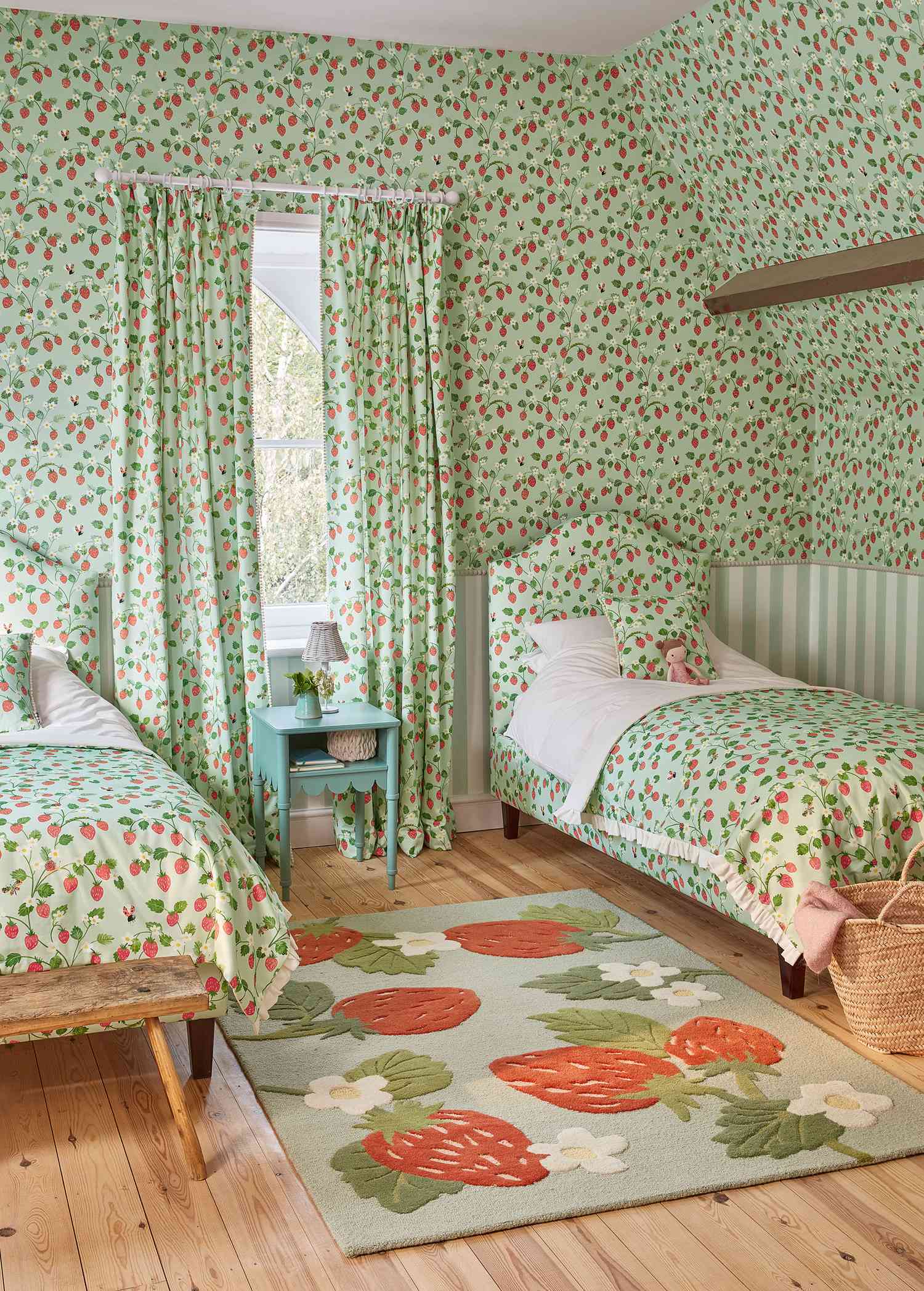 A twin bedroom covered in pale green upholstery that has a strawberry pattern. The pattern covers the curtains, bedspreads, headboards, pillows, and rug.