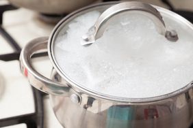 Cooking pot with lid foaming from boiling liquid on stovetop