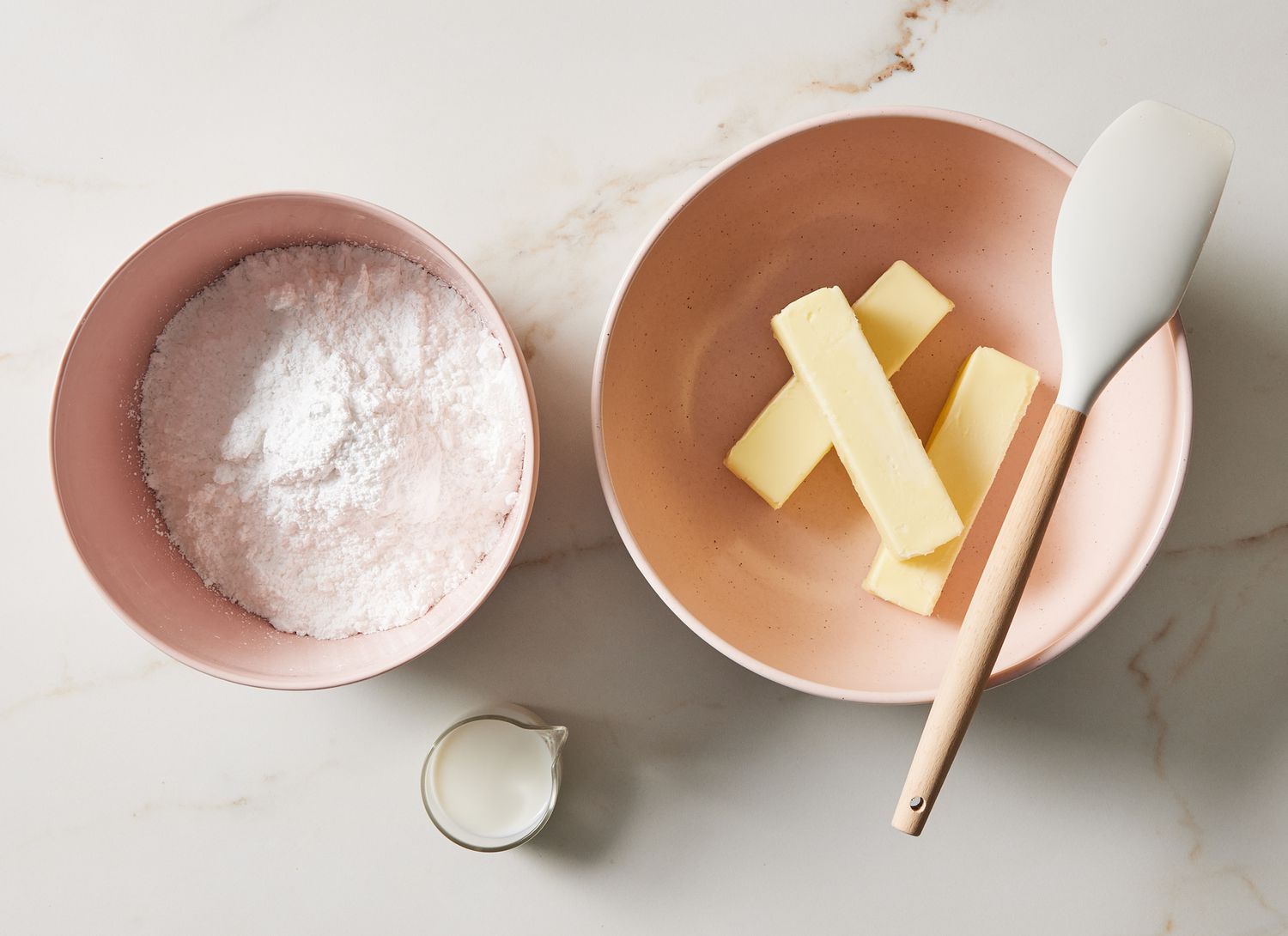 overhead view of mixing bowl with flour and bowl of butter sticks