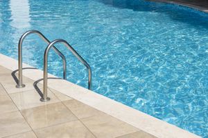 A swimming pool with a metallic ladder and tiled poolside