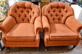 Two tufted armchairs with cushioned seats on a wooden floor