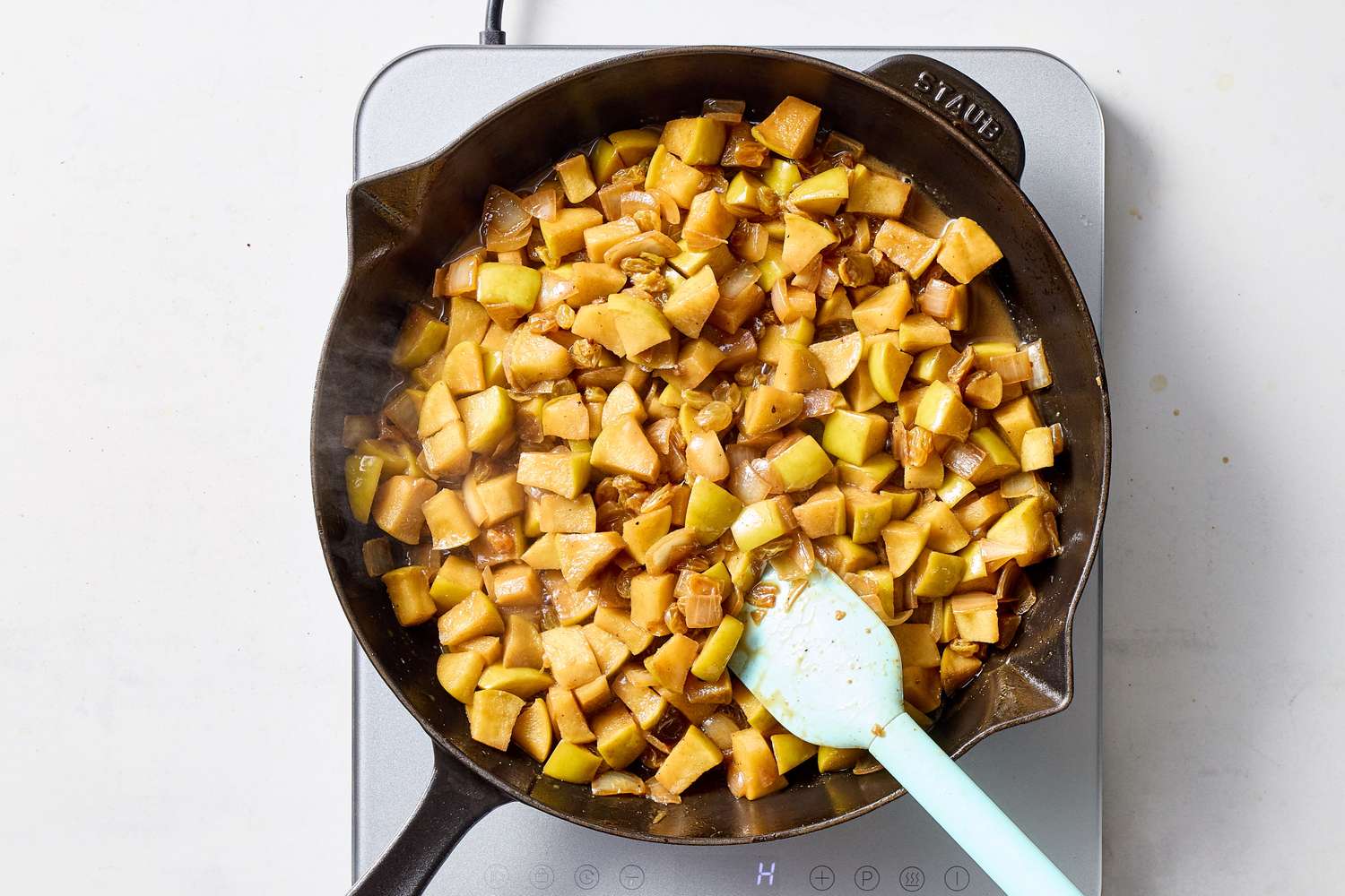 Cooking apple chutney in a skillet with a spatula next to it