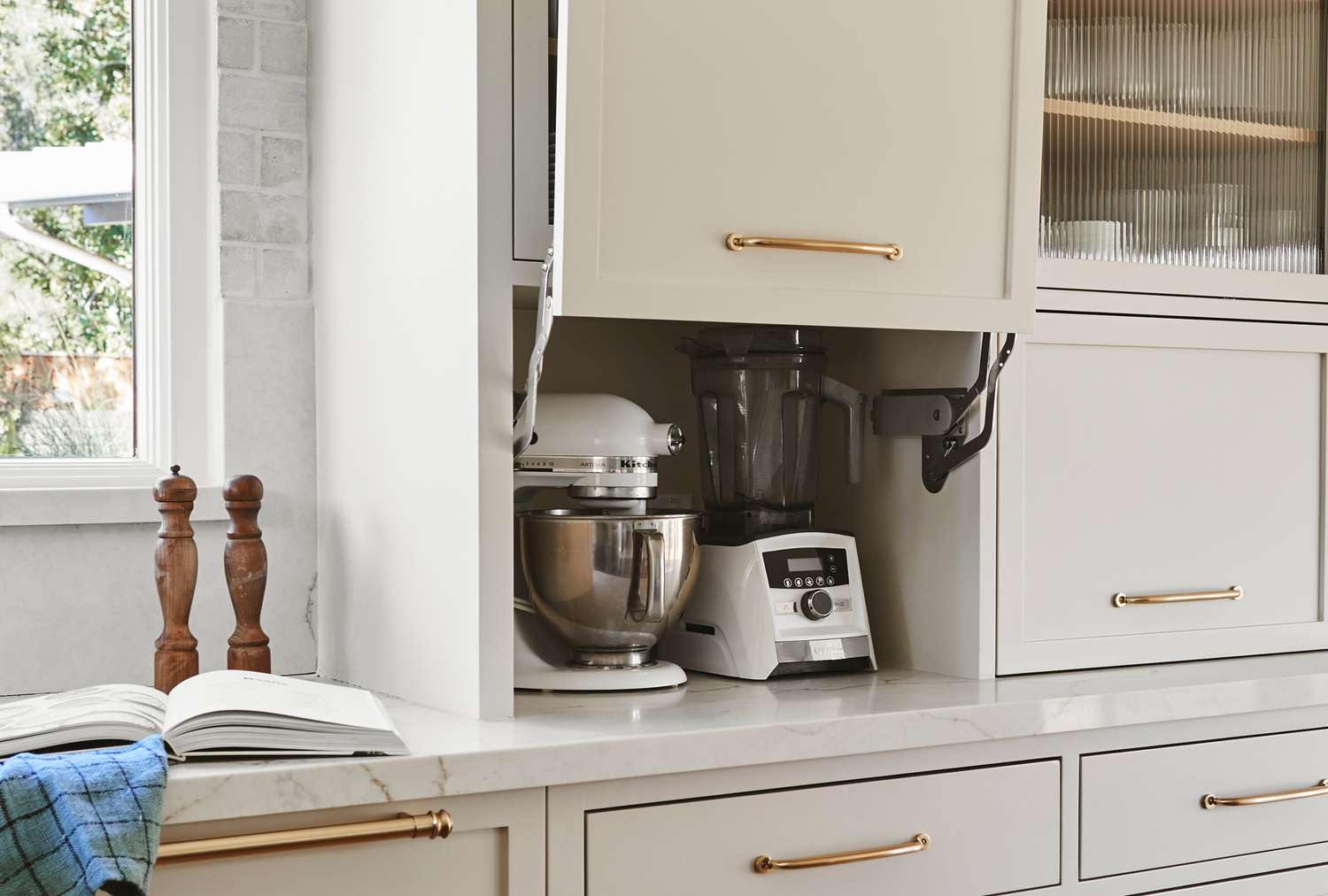 A kitchen appliance garage area with a stand mixer and blender inside a cabinet