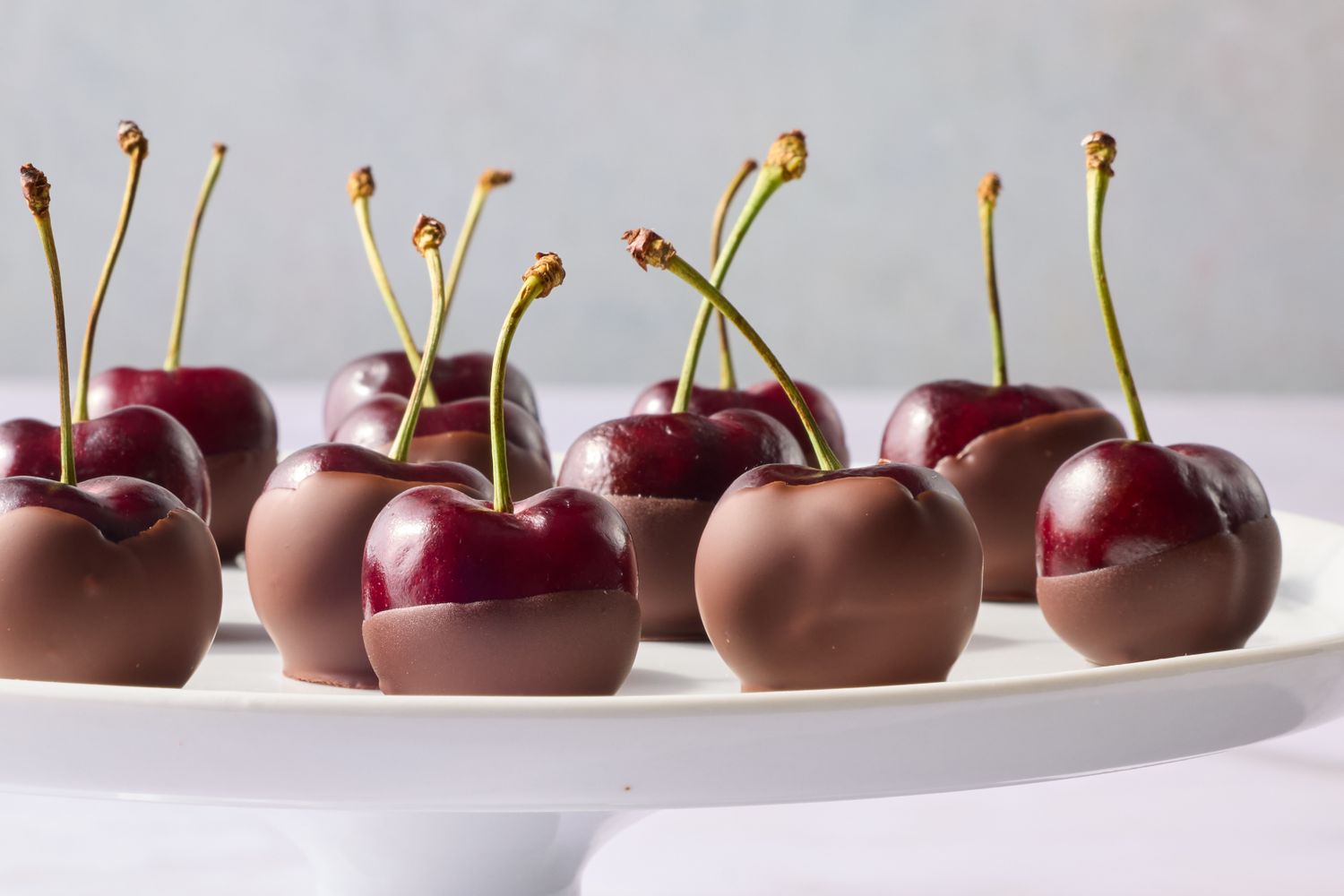 Dark chocolatecoated cherries arranged on a white platter
