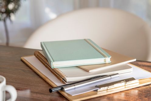 Journals notebooks and a pen arranged on a desk
