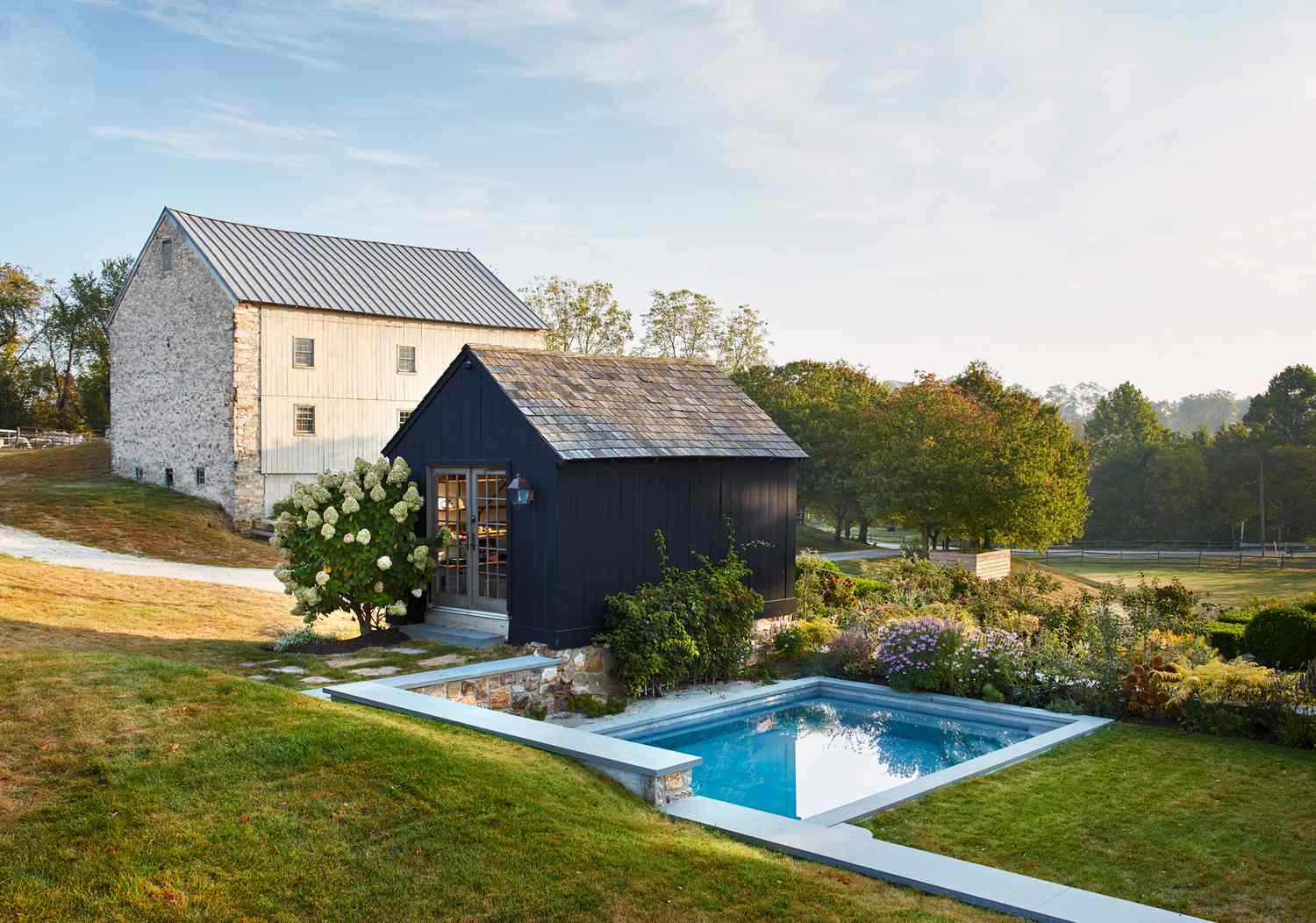 the pool and carriage house landscaped with bright flowers