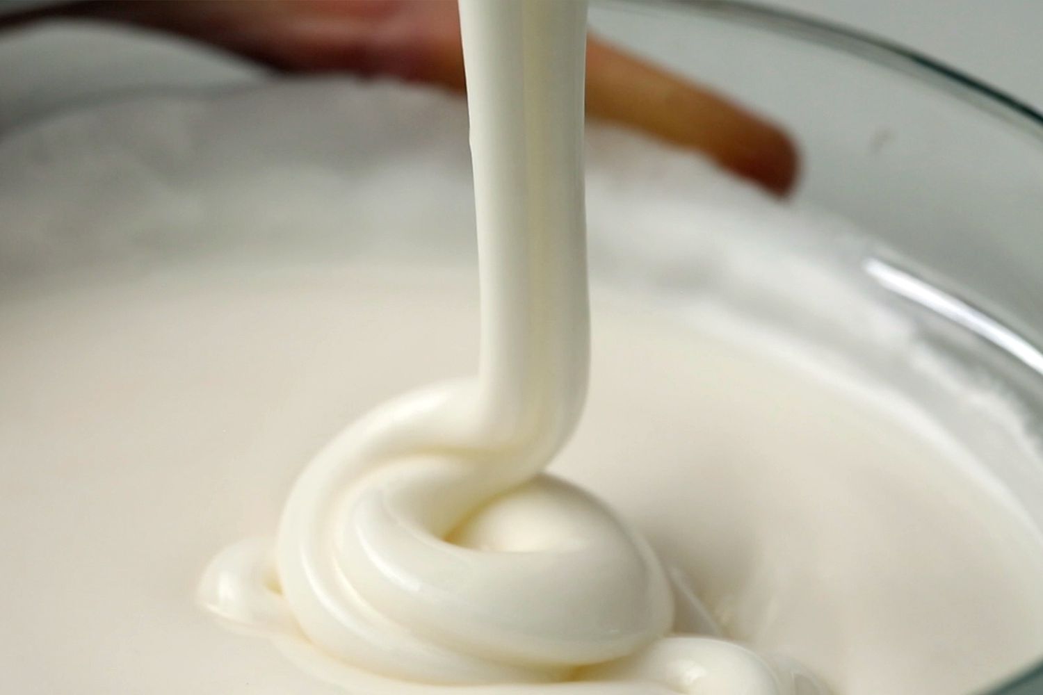 close up of frosting drizzling in a bowl
