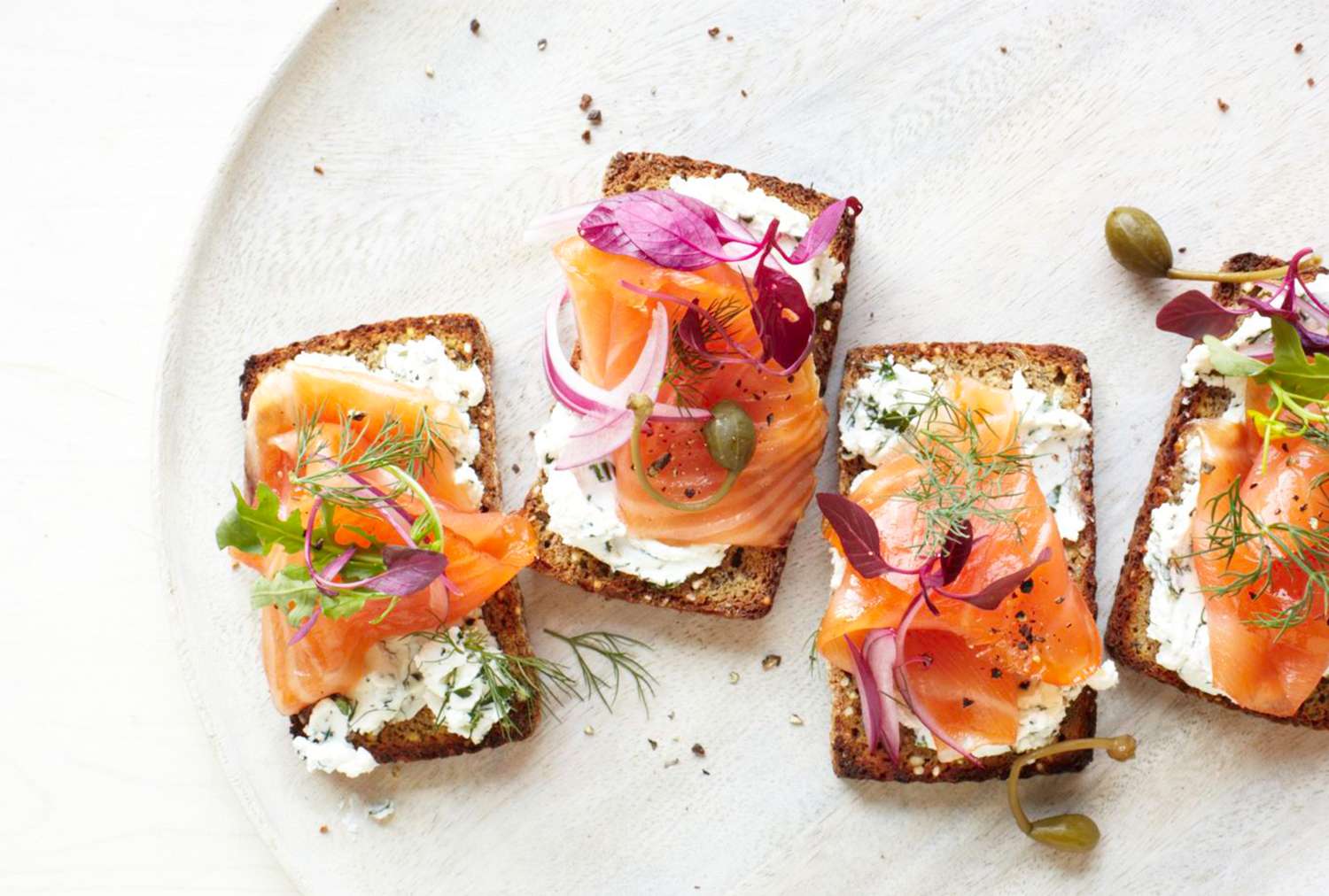 Salmon tartine garnished with herbs and toppings on a plate