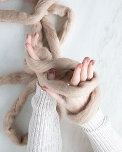 figure eight of yarn formed around hands and wrists for arm knit blanket
