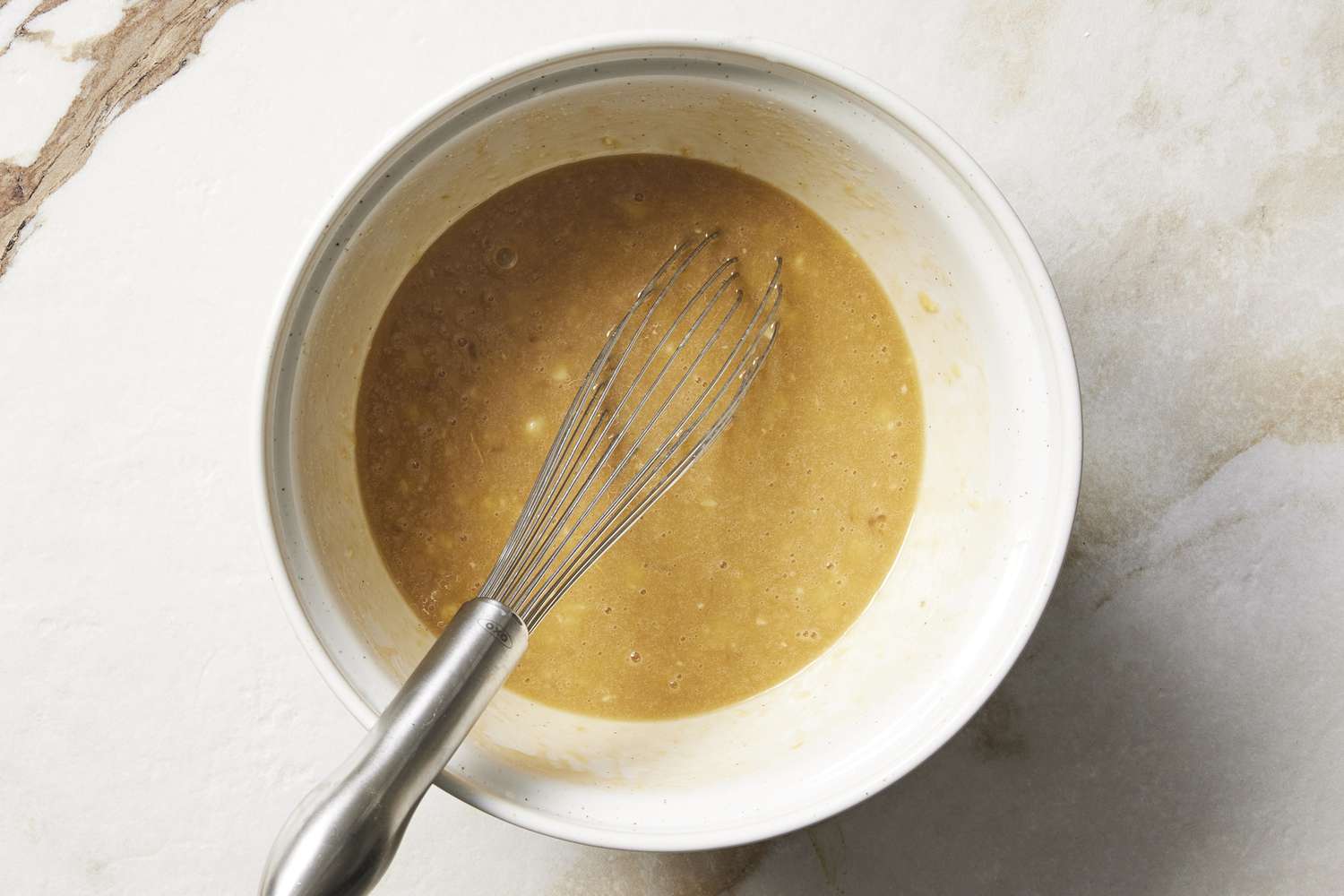Wet ingredients in a bowl with whisk