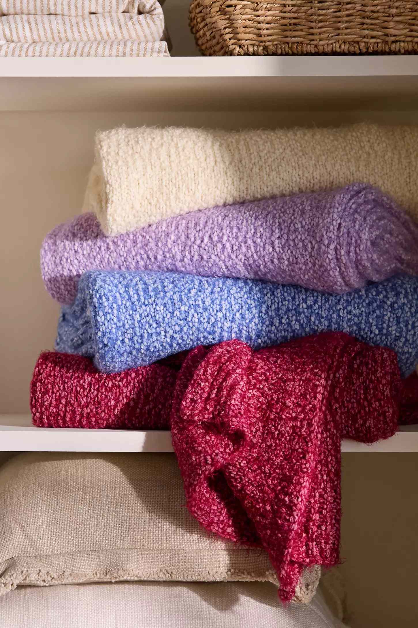 Folded textured blankets stacked on a shelf