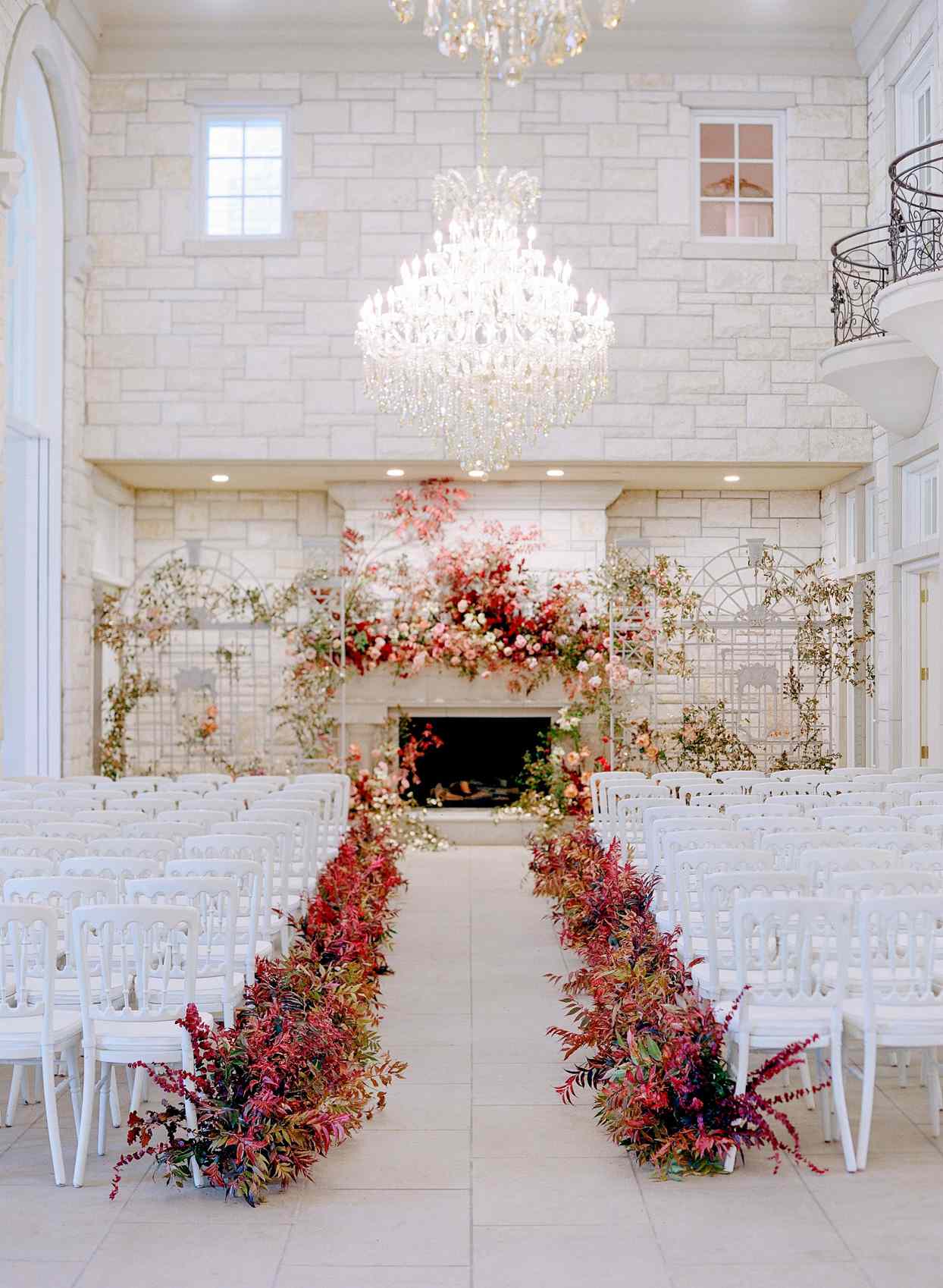 elegant indoor wedding ceremony set up with white chairs and red bouquets