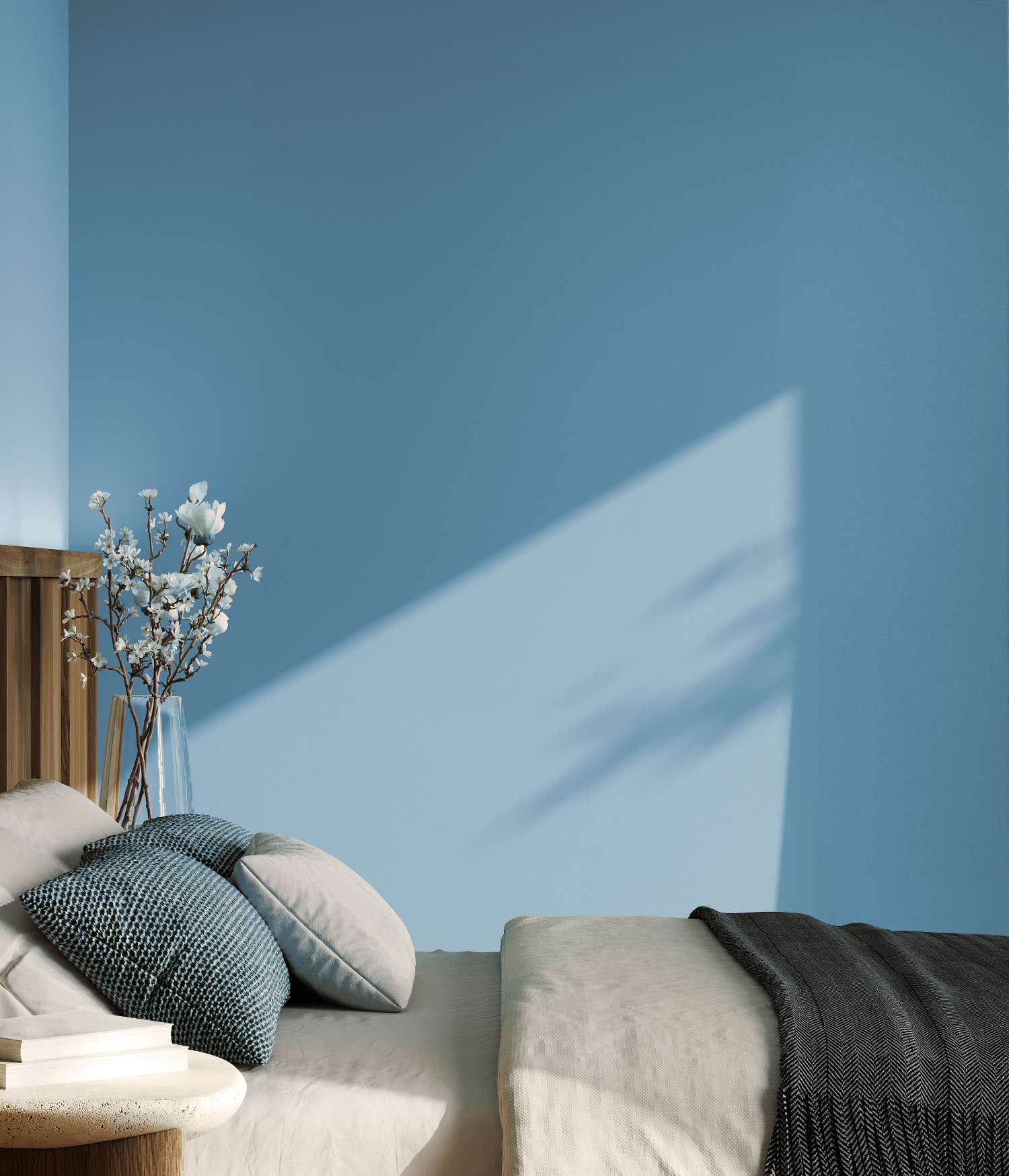 A bedroom with a neatly made bed pillows a wooden headboard and a vase of flowers on a side table