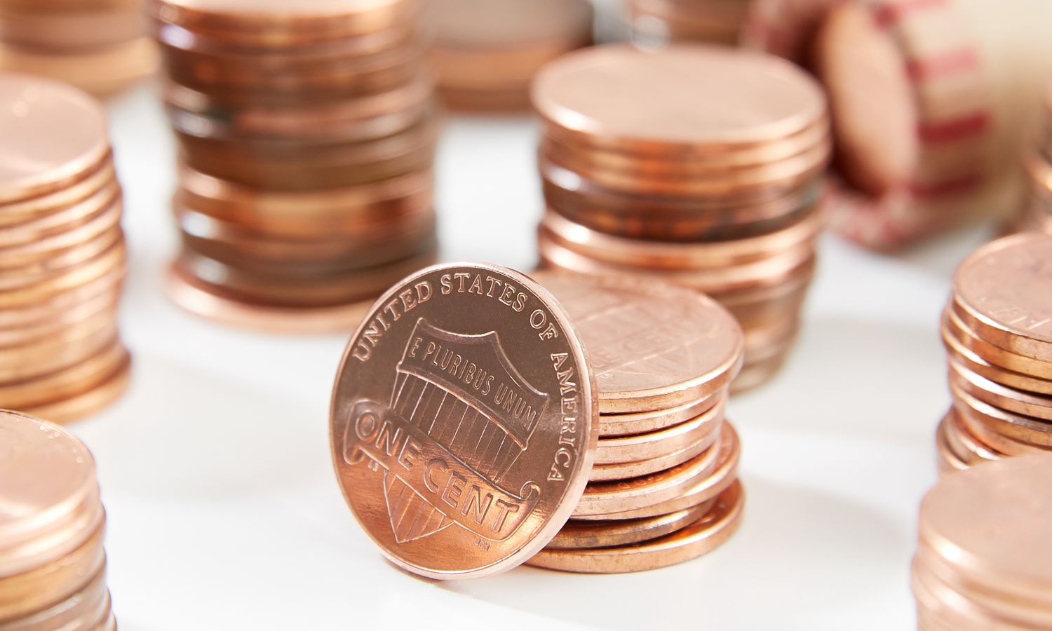 Stacks of US pennies arranged on a white surface