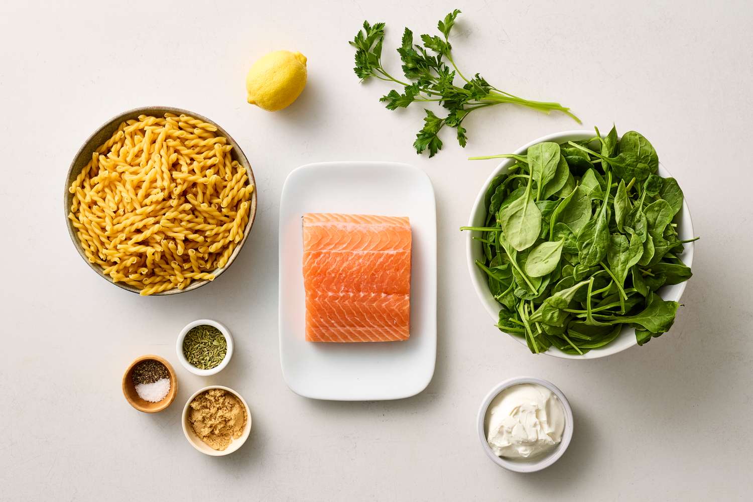 Ingredients for salmon pasta laid out including salmon pasta spinach and seasonings