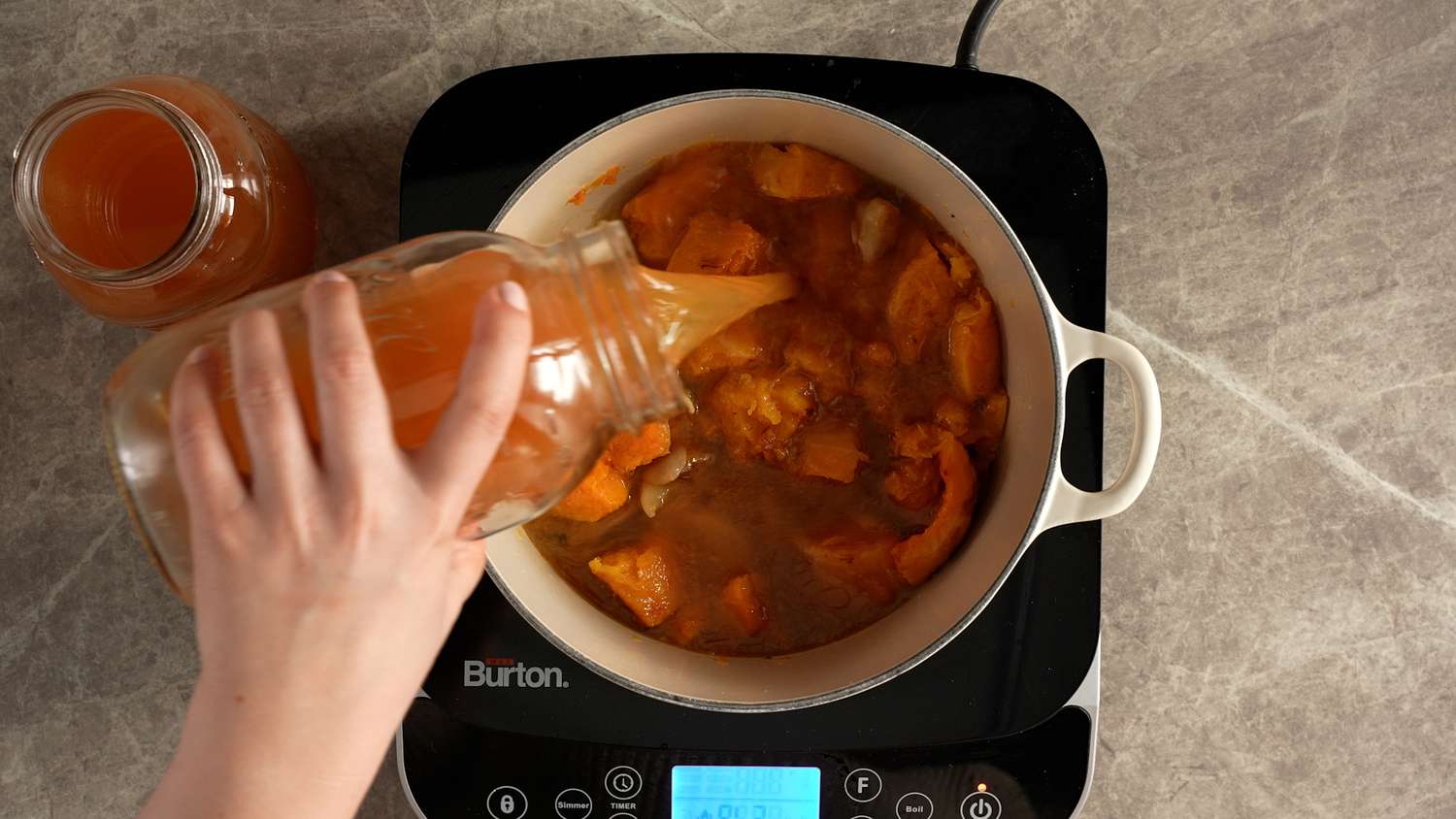 adding stock to vegetables for roasted pumpkin soup