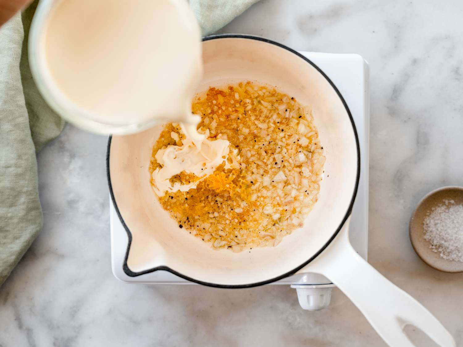 adding cream to shallots in a pan