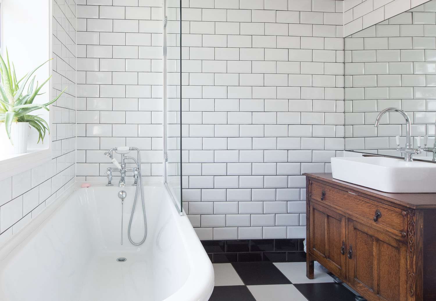A bathroom with white tile and wooden vanity