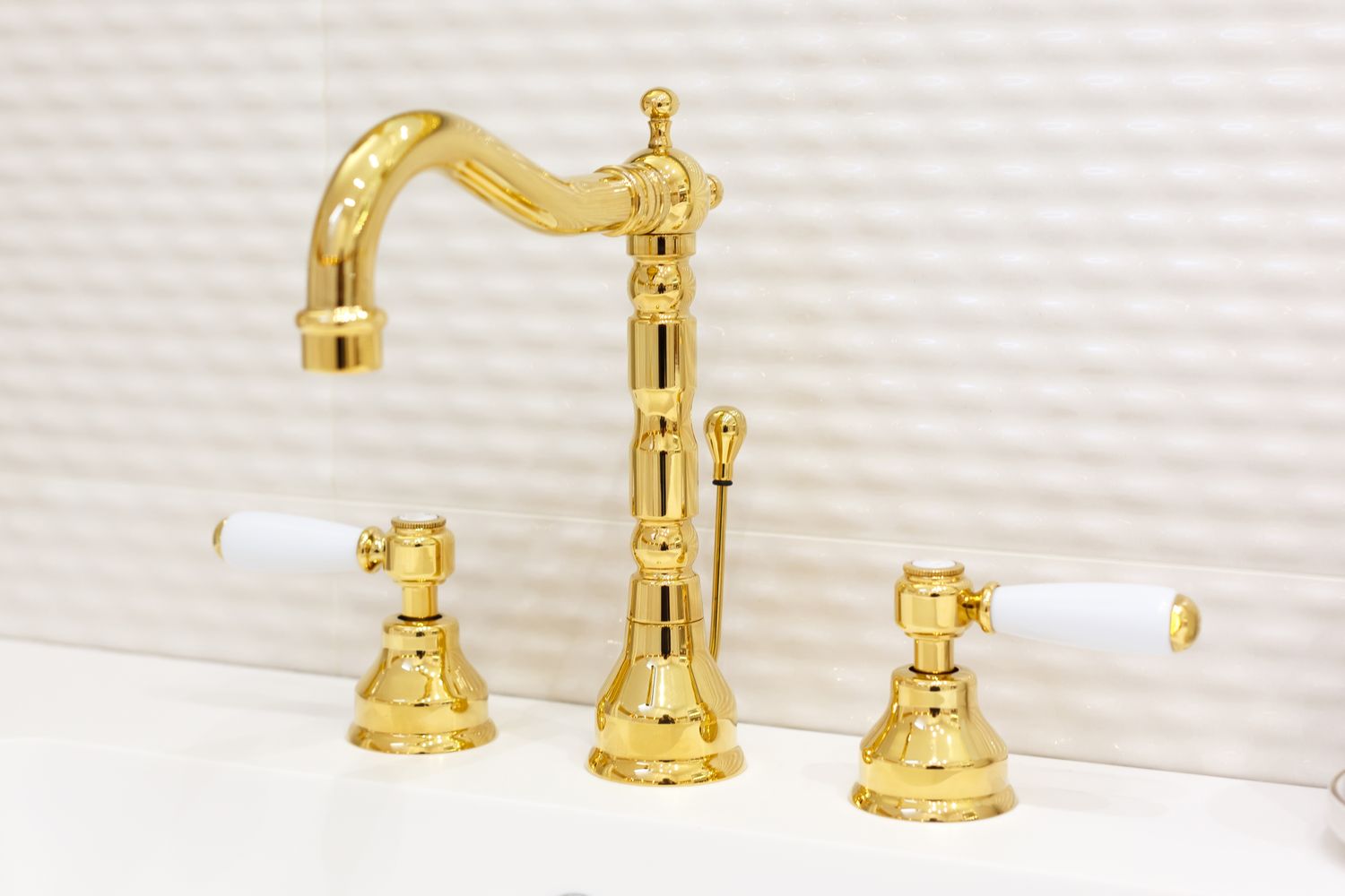 Gold faucet with two handles on a bathroom sink
