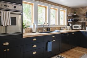 Modern kitchen with dark cabinets and wooden countertops windowed backsplash and mounted appliances
