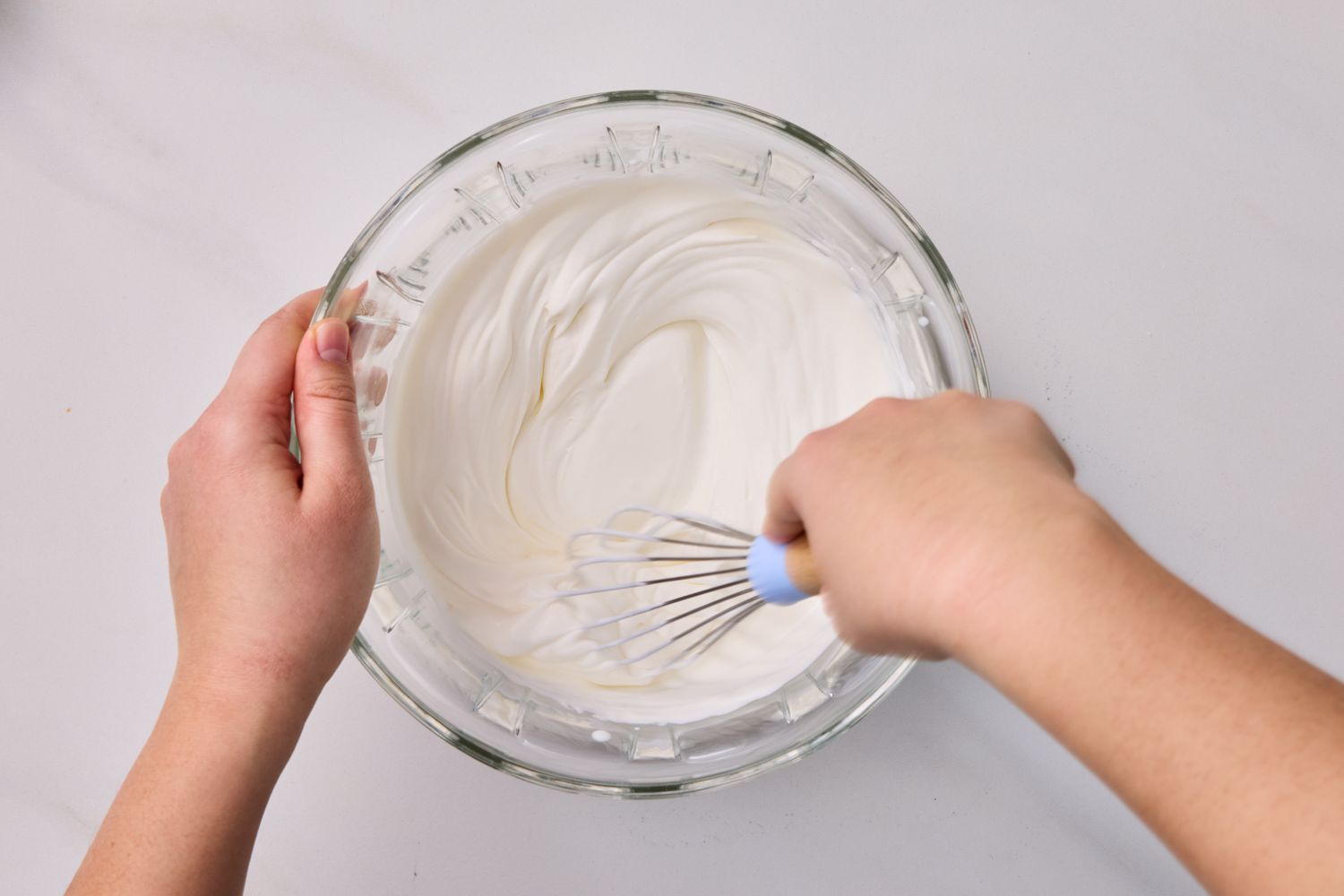 A person whisking a bowl of whipped cream
