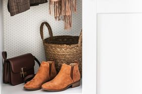 A closet shelf displaying leather ankle boots a woven basket a brown handbag and hanging clothes items