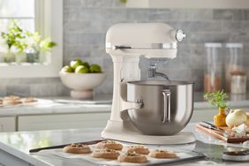 A stand mixer on a kitchen counter with cookies and ingredients