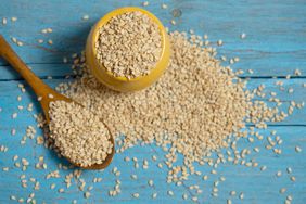 sesame seeds in spoon and on blue background