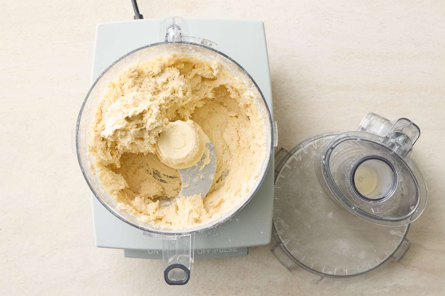 Dough mixture in a food processor next to the removed lid