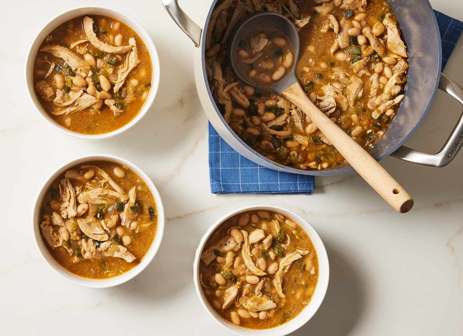 pot of chicken chili with ladle and three white bowls