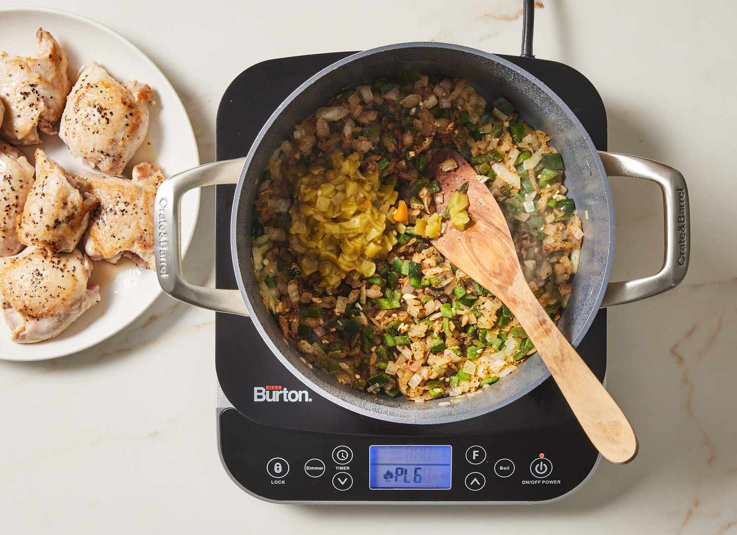 yellow and green vegetables cooking in a pot with cooked chicken on a plate