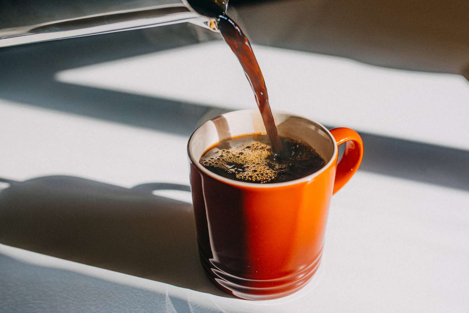 Pouring coffee into a red ceramic mug