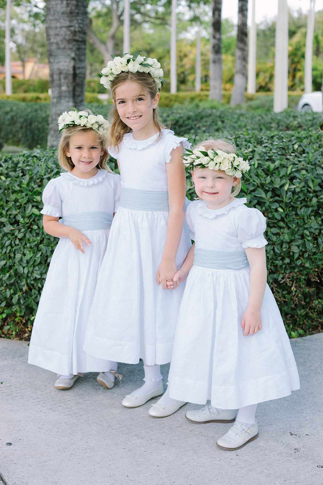 three flower girls wearing white dresses and flower crowns