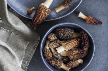 Bowls containing morel mushrooms on a surface with a cloth nearby