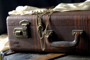 A vintage suitcase with jewelry and fabric draped over it