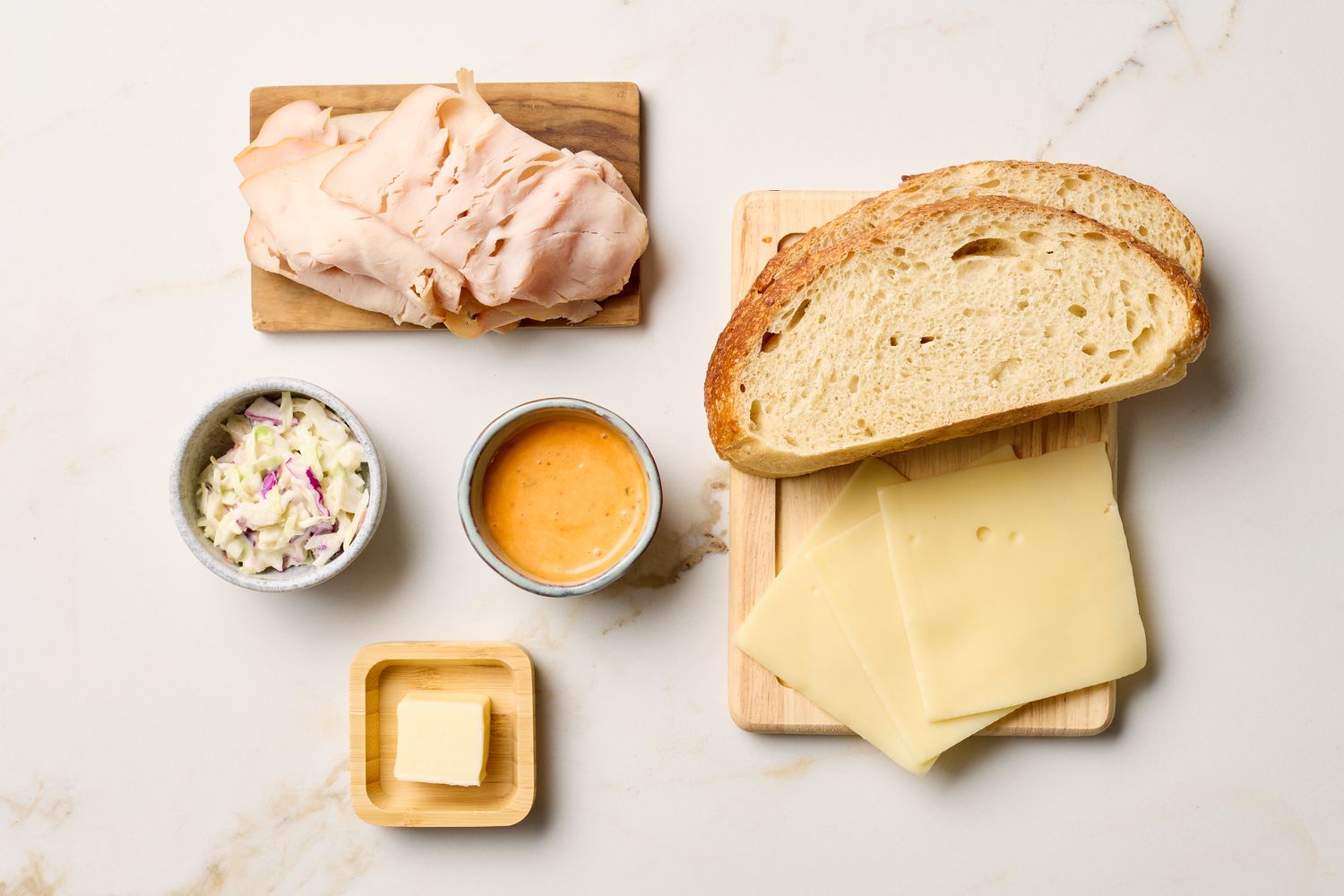 Ingredients for a Rachel sandwich including turkey coleslaw Thousand Island dressing rye bread Swiss cheese and butter