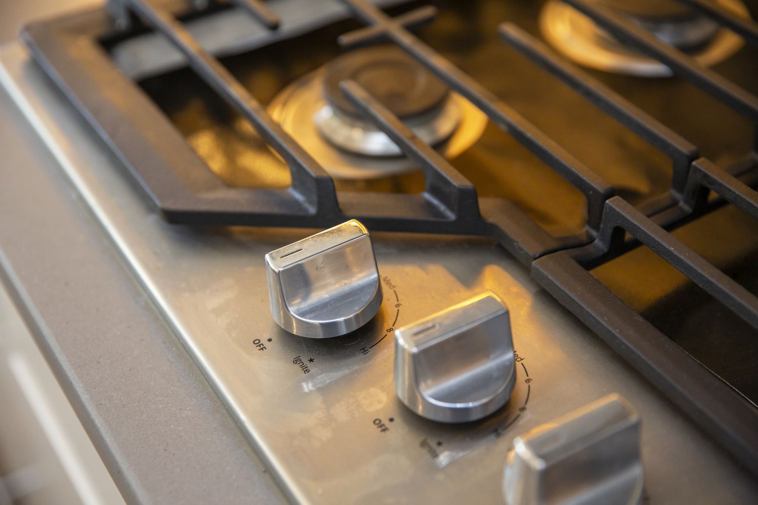 Closeup of a stovetop with metal burner knobs and grates