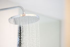 A rainfallstyle showerhead with water flowing in a bathroom