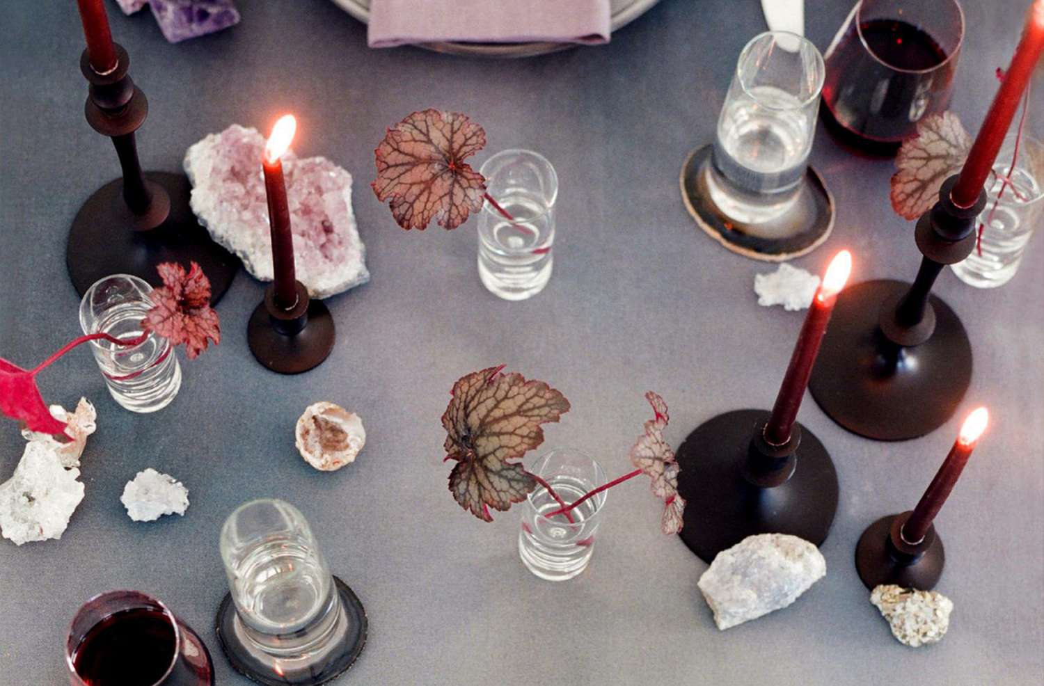 A table setting featuring decor elements like lit candles small glass vases and decorative stones