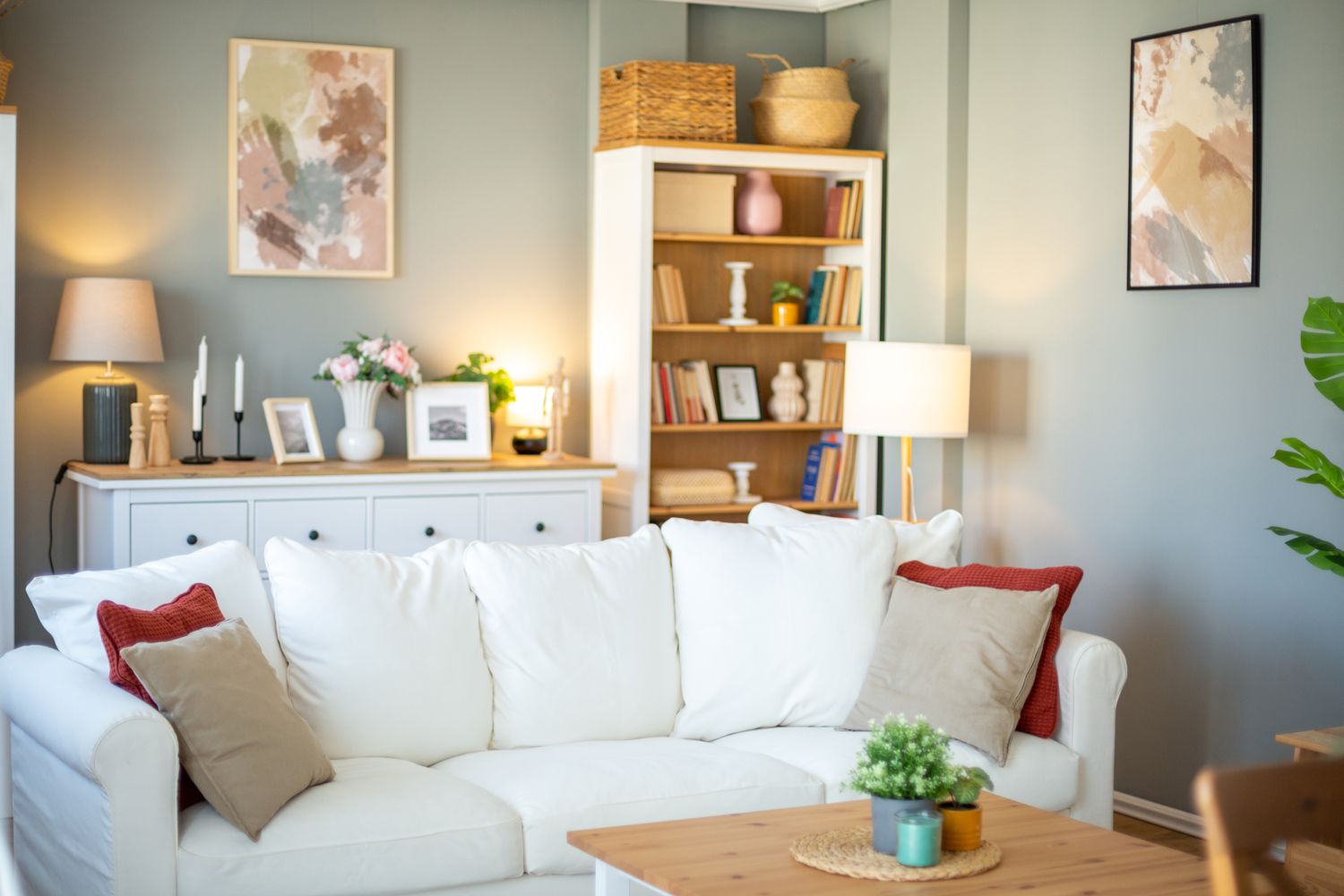 A cozy living room with a white sofa and decor items on shelves behind it
