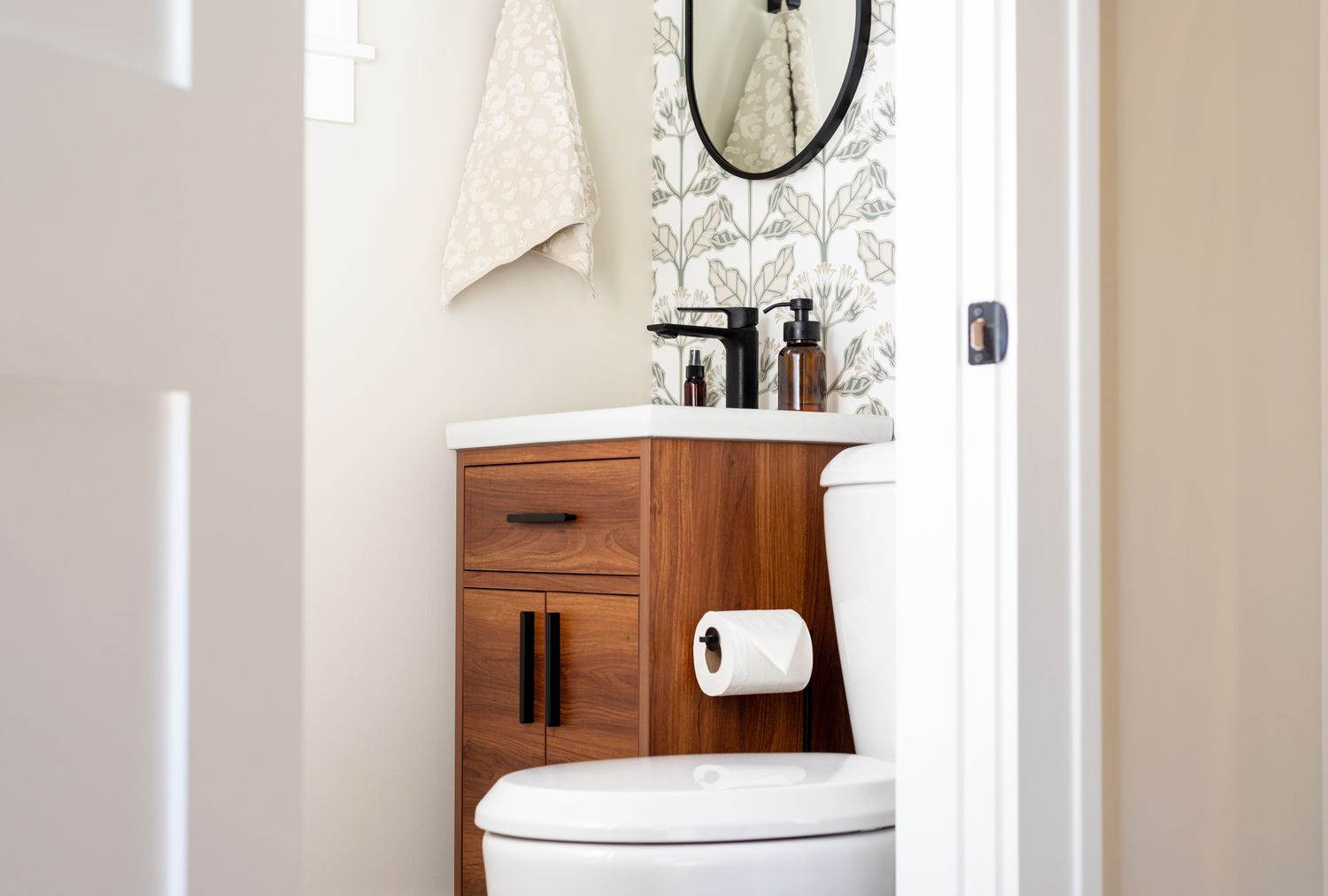 A small bathroom with a wooden vanity cabinet a round mirror and a toilet