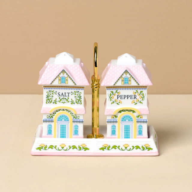 Decorative salt and pepper shakers shaped like small houses displayed on a base with a handle in the center