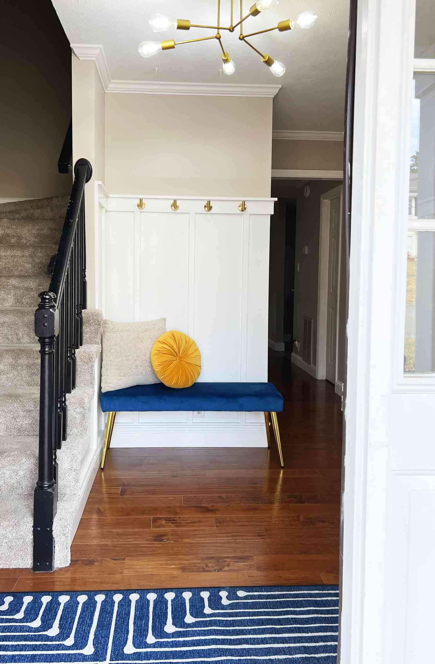Entry way with blue bench, yellow pillow and gold light fixture